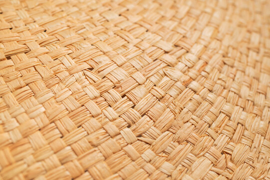 Detailed braided fiber surface fills frame with repeating natural strands and warm neutral color. Braided texture offers versatile visual material for craft, decor, fashion and eco branding.