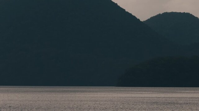 Gray ripples on Lake Toya with a dark blue island silhouette
