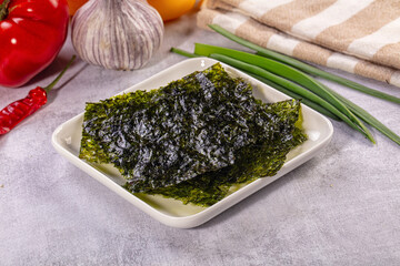Roasted seaweed sheets on white plate with fresh vegetables and kitchen towel © Andrei Starostin