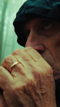 Sad Old Man Warms His Hands on a Foggy Autumn Day in the Mountains