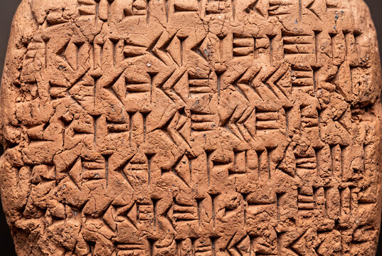 Cuneiform tablet macro with wedge impressions on solid warm terracotta background