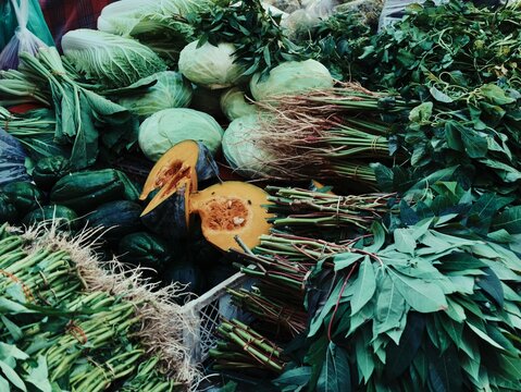 Wide display of fresh tropical vegetables pumpkin cabbage and leafy greens at Indonesian market
