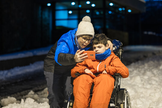 Mother and child watching smartphone outdoors in snow