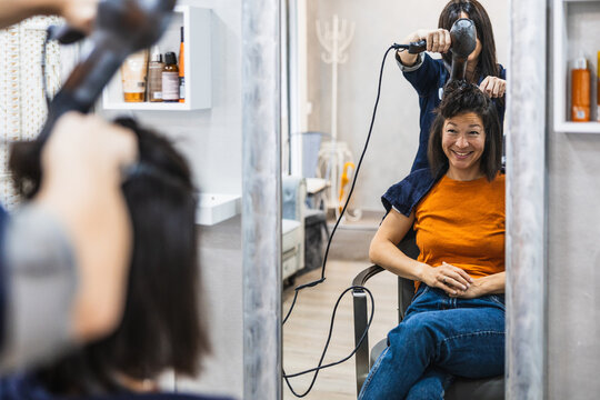 Happy woman having hair styled at salon