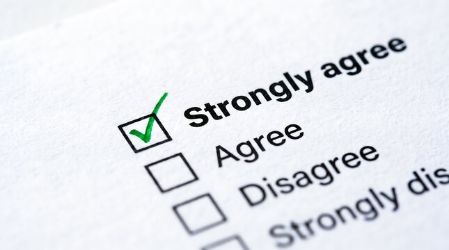 Green checkmark in the strongly agree box of a customer opinion survey paper close up macro view.