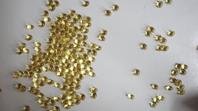 Vitamin A softgel capsules forming a large letter A are swept apart by hand creating a dissolving letter effect and visualizing changing supplement and wellness habits daily