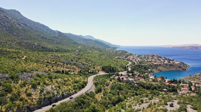 Cars driving on winding road through villages near sea