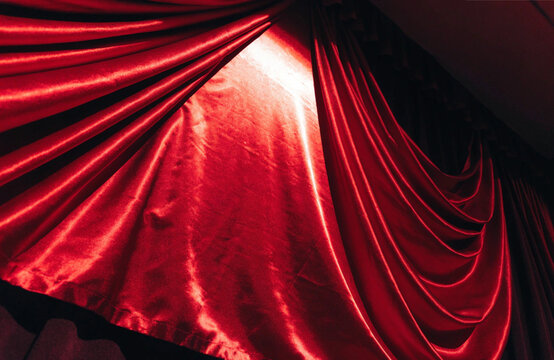 Red curtain stage illuminated by a spotlight in a dark theater