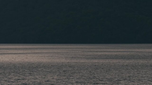 Gray ripples on Lake Toya with a dark blue island silhouette
