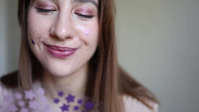Young woman smiles while choosing purple star shaped acne patches for her face creating a playful skincare routine focused on blemish care and confident everyday beauty