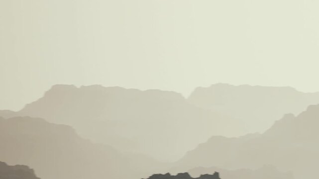 A view of mountain ranges and hills is captured in soft light as the day begins. The landscape shows layered shapes against a light sky, suggestive of early morning.