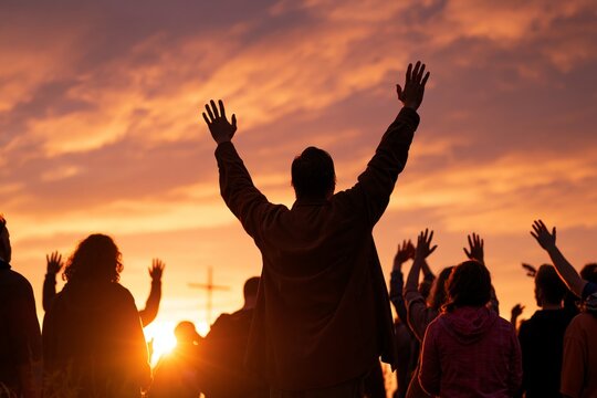 Silhouettes of people raising hands in worship during vibrant sunset with cross visible in distance under dramatic amber and violet sky, group gathered outdoors in spiritual reflection