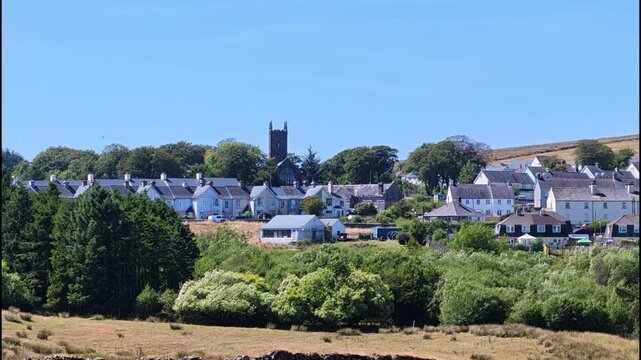 Princetown Dartmoor Devon UK. 11.08.2026. Video.  Princetow. A scenic view of a quaint village with traditional houses and a prominent church tower, surrounded by lush greenery and rolling hills