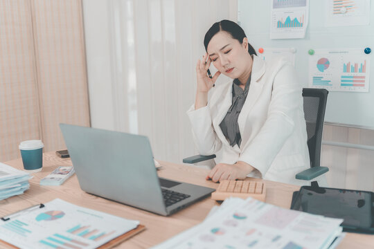 Stressed Asian Businesswoman Holding Head in Pain Having Headache at Desk