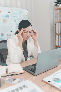 Stressed Asian Businesswoman Holding Head in Pain Having Headache at Desk