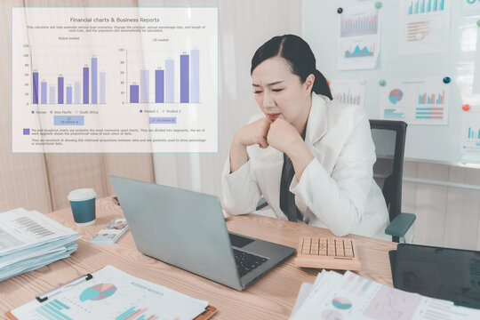 Asian Businesswoman Working on Laptop and Taking Notes at Desk in Office