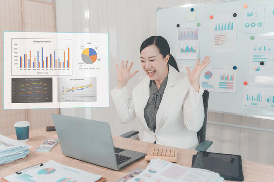Asian Businesswoman Working on Laptop and Taking Notes at Desk in Office