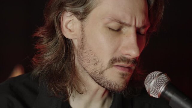 A guy in a black shirt is singing into the microphone.