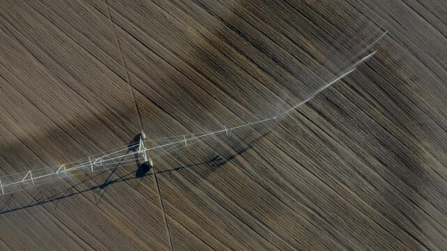 Drone aerial of a center pivot irrigation system watering drought-affected farmland in Hungary, highlighting modern agriculture and water management.