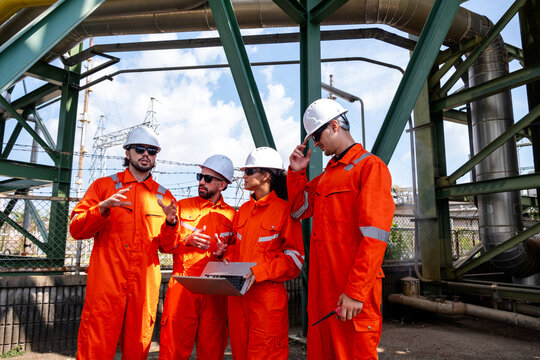 Workers discuss plans near industrial equipment during daylight hours in an active facility