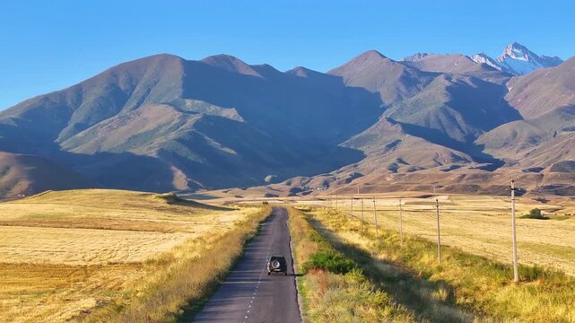 The car on the road to the mountains. Landscape with tarmac road near high mountains. Drone video of mountain area in summer.