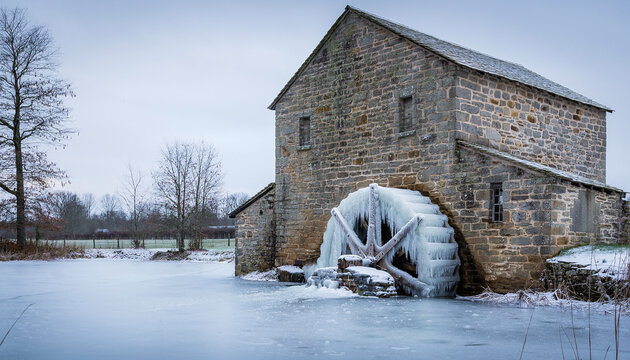Old Stone Flour Mill with Frozen Water Wheel in Winter