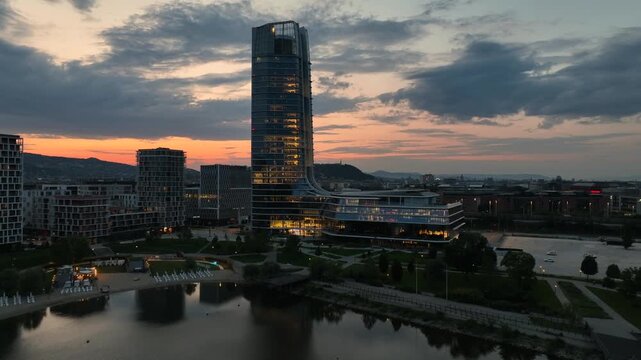 Drone aerial of the MOL Campus in Budapest, Hungary, illuminated at sunset with the modern skyscraper dominating the city's skyline.