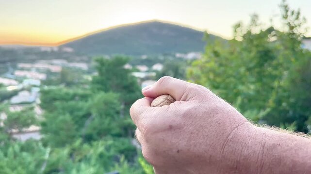  A horizontal video showing a close-up of a man's hand popping open a champagne or sparkling wine bottle with a scenic mountain landscape and sunset in the blurred background.