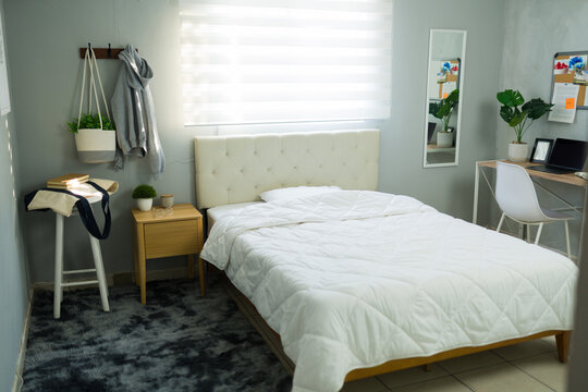 Modern bright bedroom interior with minimalist design, comfortable bed and home office workspace creating a cozy living space