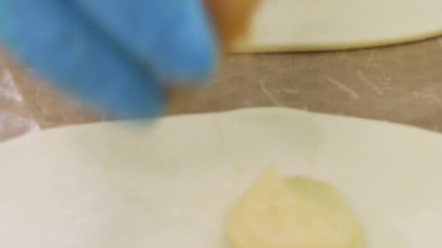 Close low-angle view of pastry assembly with two fillings placed on dough rounds across trays in commercial kitchen, with pastry, dough, filling, bakery detail, showing preparation, baking, assembly