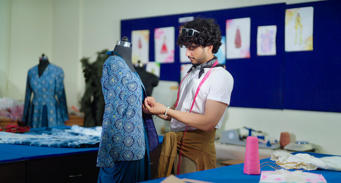 Indian happy young adult gen z male man wear tape around neck do work good indoor class room. Smart teen pupil boy do create new dummy dress clothe craft learn skill course day college place