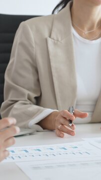 Business team analyzing financial data and discussing marketing strategy during a meeting in the office, businesswoman pointing at charts and explaining strategy to colleagues