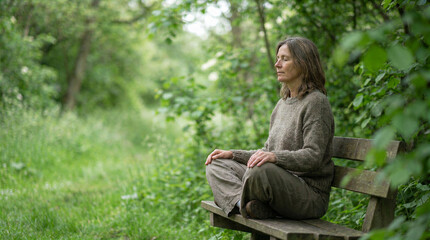 Obraz premium Woman meditating cross legged on park bench in forest setting for mindfulness concept