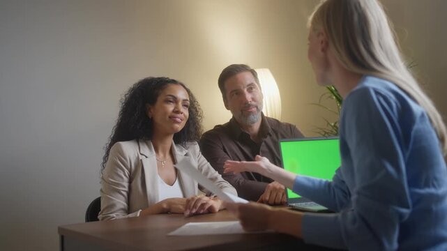 Waist up of young multiracial married couple visiting insurance agent in her modern office, wanting to sign insurance policy