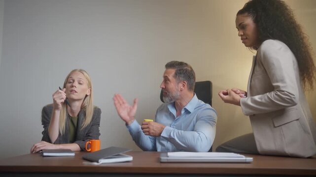 Bored female colleagues ignoring talkative male coworker during office coffee break