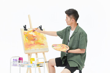 Young male artist painting abstract artwork on easel in bright studio © DaoYenThu