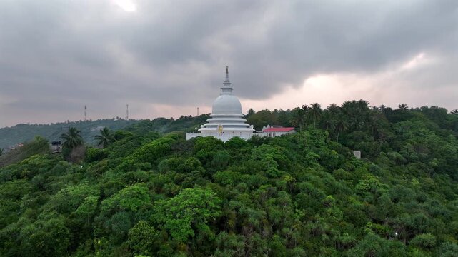 Drone aerial of the Japanese Peace Pagoda on Rumassala Hill, Unawatuna, Sri Lanka, overlooking the Indian Ocean and the tropical southern coastline.