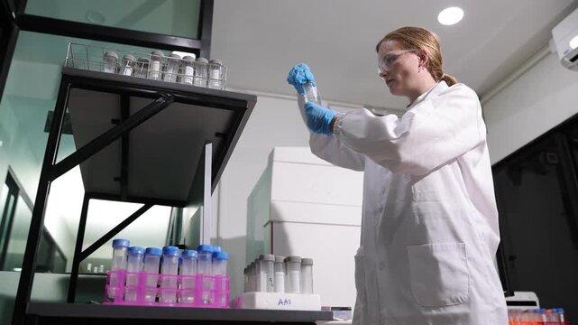 Dedicated female biochemist carefully handling a test tube containing a specimen while working on a scientific experiment in a laboratory.