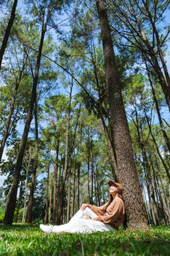 Vertical portrait image of a woman sitting and relaxing in the park