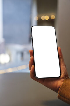 Vertical mockup image of a woman holding mobile phone with blank desktop screen in cafe