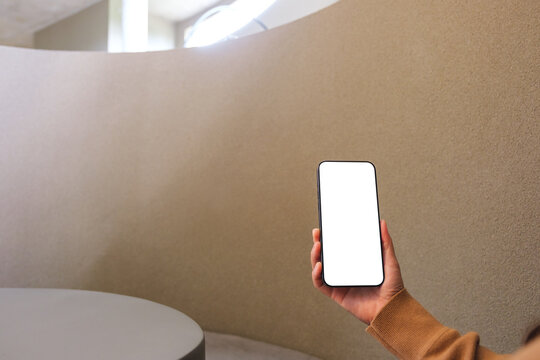 Mockup image of a woman holding mobile phone with blank desktop screen in cafe