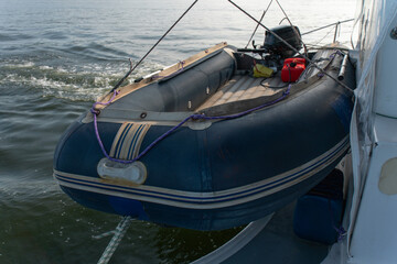Inflatable motorboat with outboard engine is secured alongside catamaran while sailing on open water. Marine transport, boating equipment, safety, adventure travel, tourism © Sofia