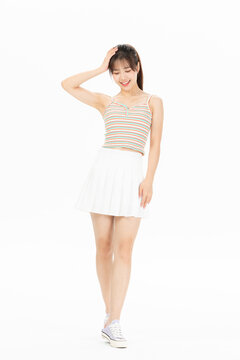 Smiling young woman in striped camisole and white skirt posing on white background