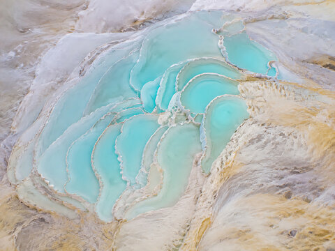 Aerial view of pamukkale thermal pools with turquoise water in white travertine terraces, natural limestone formations in a landscape setting