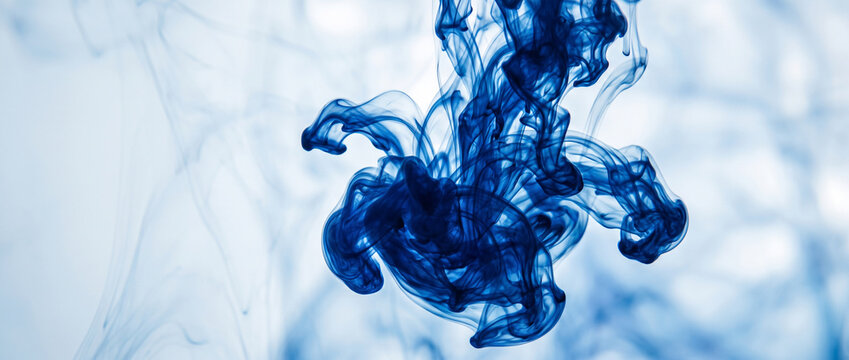 Blue ink swirling in clear water, abstract liquid cloud background for creative design.