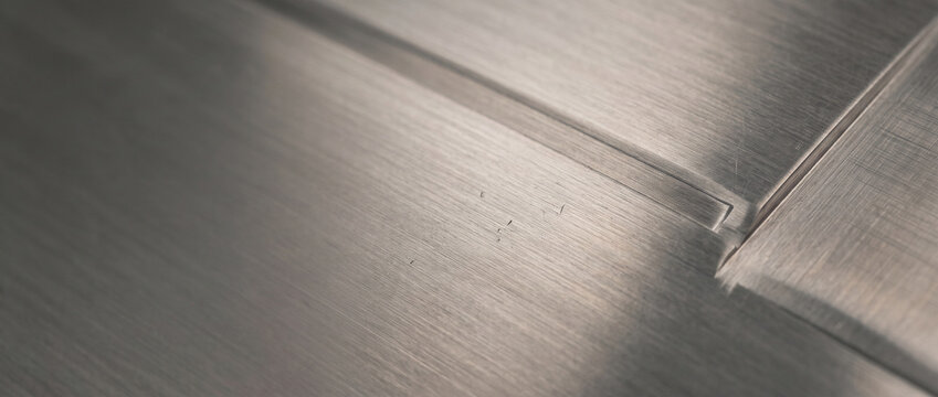 Close up of brushed metal surface with a weld seam and industrial texture detail.
