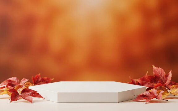 White hexagonal display platform with autumn leaves on blurred orange background