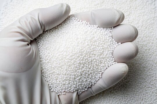 Gloved hand holds white plastic polymer pellets. Small granules fill palm, representing raw material for manufacturing. This raw plastic signifies production, industry, and chemical compounds.