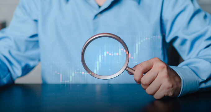 investment, stock analysis, economic growth, financial research, and market strategy. Business professional analyzing financial market trends with a magnifying glass over a digital chart.