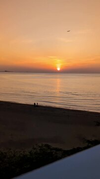 A serene wide shot of a vibrant golden sunrise reflecting over a completely calm ocean surface.